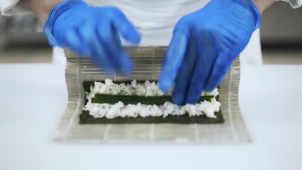Hands of chef putting cucumber on rice making sushi — Stock Video