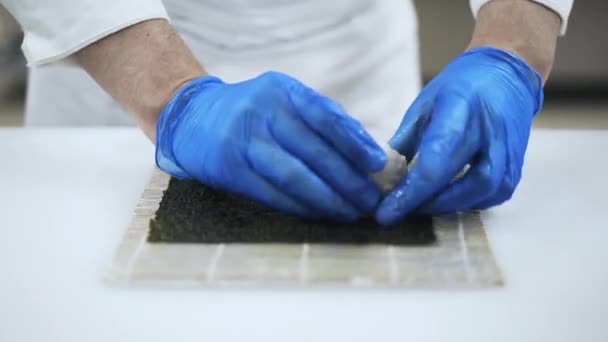 Руки шеф-кухаря кладуть рис на морські водорості — стокове відео