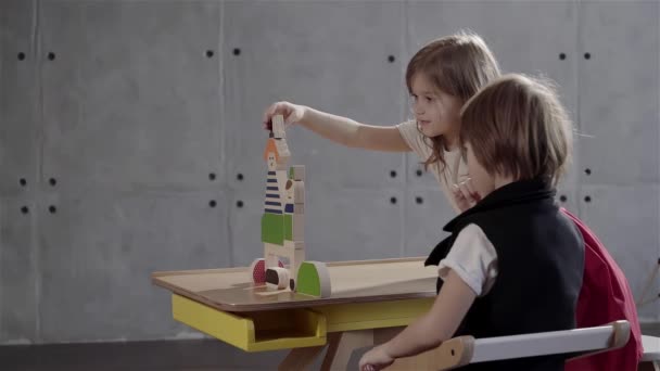 Брат и сестра играют с деревянными кирпичами — стоковое видео