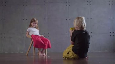 Sarışın küçük çocuk bir fotoğraf gri bir odada oturan küçük bir kızın yapma