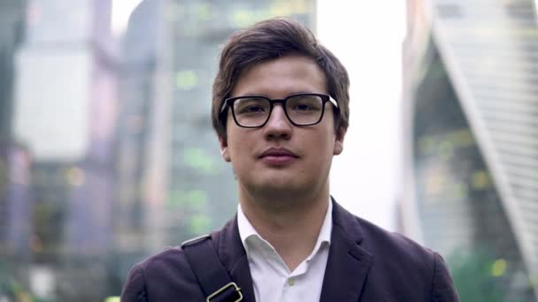 Calmo jovem empresário retrato, sorrindo para a câmera em uma cidade grande, verão — Vídeo de Stock