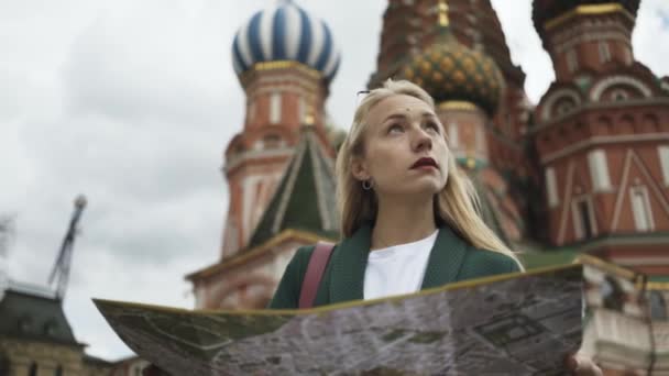 Leende blondin turist tittar på karta står nära Kreml, Ryssland sommaren — Stockvideo