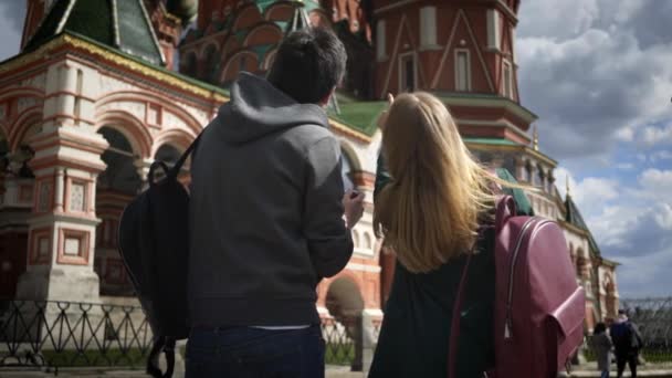 Οπίσθια όψη νεαρό ζευγάρι τουριστών λαμβάνοντας εικόνες από τον καθεδρικό ναό της Μόσχα, Κρεμλίνο — Αρχείο Βίντεο