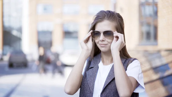 A close up of a young smiling girl is wearing sunglasses outside