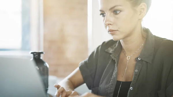 Een leuke ernstige witte vrouw is werken met een laptop — Stockfoto