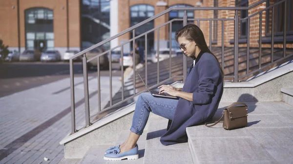 Una giovane ragazza con gli occhiali da sole sta lavorando sulle scale all'aperto — Foto Stock