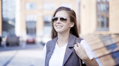 Bir genç gülümseyen kız açık havada gözlük takıyor