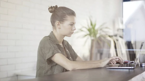 Una giovane ragazza piuttosto seria con un computer portatile seduto a un tavolo — Foto Stock