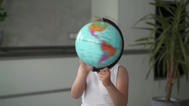 Pequeña irreconocible girando un globo en casa — Vídeo de stock