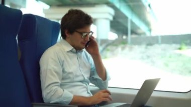 Yakışıklı genç işadamı telefon ve dizüstü bir tren kullanma