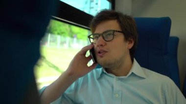 Orta yaş işadamı bir tren sürme ve telefonda konuşurken gözlük