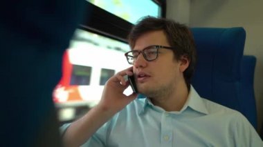 Orta yaş adam telefonda konuşurken ve gülümseyen bir tren sürme gözlük