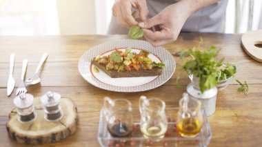 Bir erkek Şef yeşillik bir güveç salata siyah bir ekmek parçası üzerinde ekleme