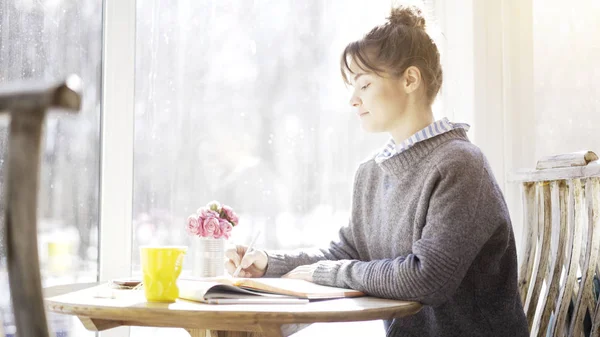 Un profilo di una giovane ragazza bruna sta leggendo guardando in un notebook nel caffè — Foto Stock