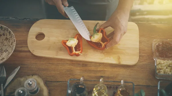 Manliga händer skivning en röd paprika på en matlagning ombord — Stockfoto