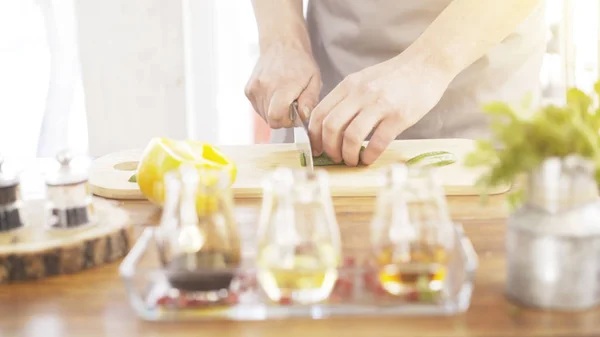 Manliga spisar händer skära gurka på en träskiva matlagning — Stockfoto