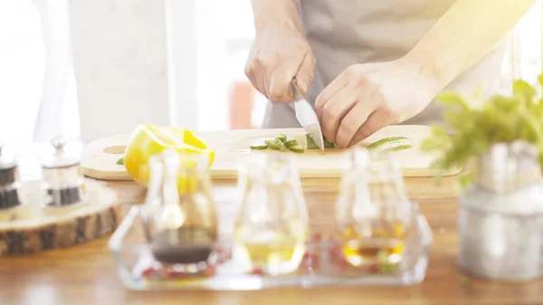 Manliga spisar händer skära gurka på en träskiva matlagning — Stockfoto