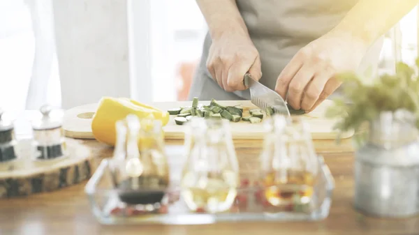 Manliga spisar händer skivning gurkor på en träskiva matlagning — Stockfoto