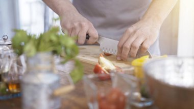 Erkek Şef Dilimleme kiraz domates ahşap kesme tahtası üzerinde eller