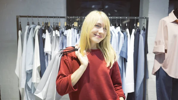 Une jeune femme blonde souriante et heureuse vient d'acheter des vêtements dans un magasin — Photo