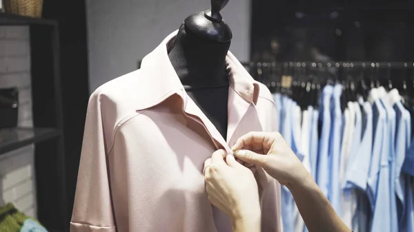 Un gros plan des mains blanches féminines boutonnant un manteau rose sur un mannequin — Photo
