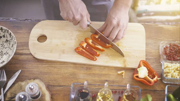 Manliga händer skivning en röd paprika på en matlagning ombord — Stockfoto