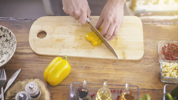 Manliga händer skivning en gul paprika en matlagning ombord — Stockfoto