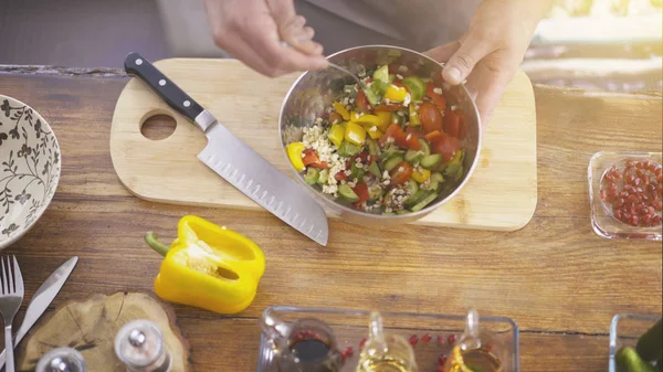 Manliga spisar händer blanda gurka med tomater i en Salladsskål — Stockfoto