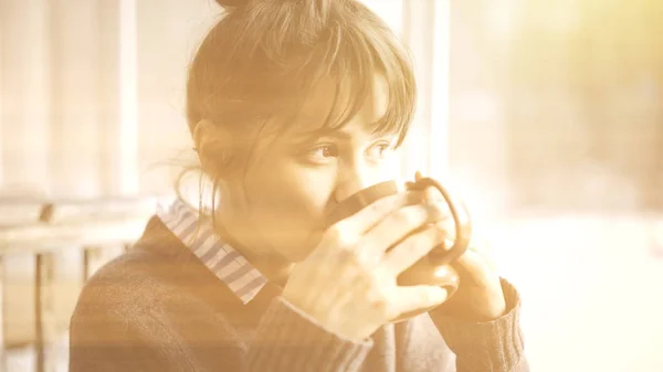 Un primo piano di bianco femminile bere in possesso di una tazza di tè guardare la finestra — Foto Stock