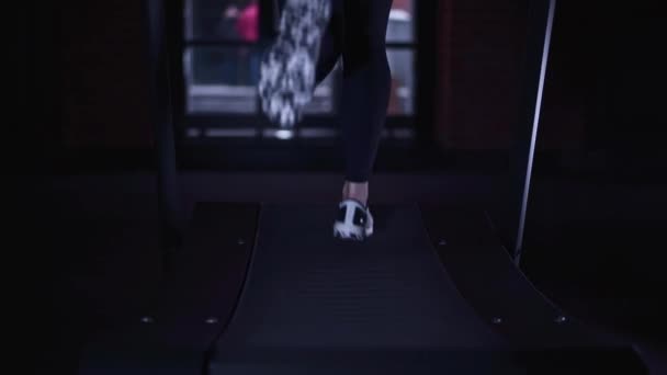 Patas de mujer en zapatillas blancas en cinta de correr, vista trasera lenta mo — Vídeos de Stock