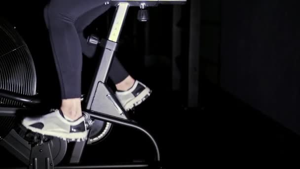 S benen van de vrouw in witte sneakers op de machine van een fiets in een sportschool, langzame mo zijaanzicht — Stockvideo