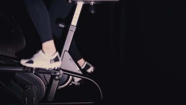 Жінка ноги в білих кросівок на велосипедній машині в спортзалі, вид збоку, сковорідка — стокове відео