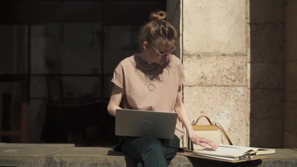 Mooie jonge vrouw met laptop en boeken buiten, zomer studeren — Stockvideo