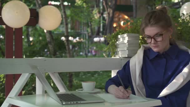 Unga kaukasiska affärskvinna skriver i ett sommarcafé. Affärsstrategi — Stockvideo