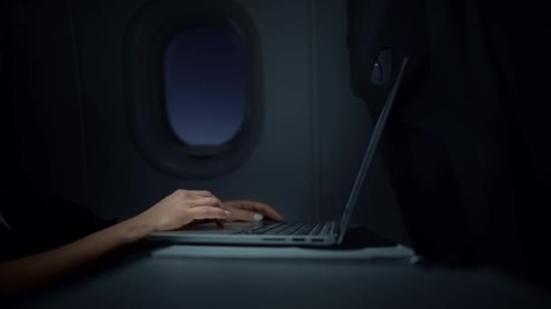 Mulher de negócios irreconhecível trabalhando com seu laptop em um avião noturno — Vídeo de Stock