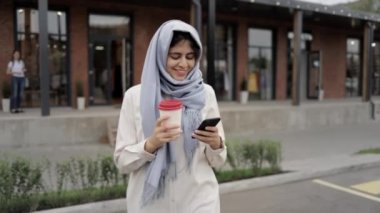 Kahve içme ve smartphone vasıl seyir gri hijab genç kadın