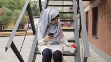 Hijab merdivenler dışında mesaj üzerinde oturan genç kadın