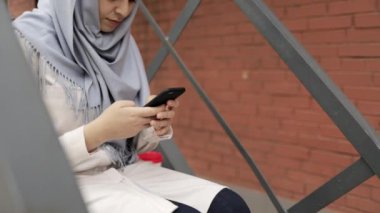 Hijab merdivenler dışında mesaj, tilt üzerinde oturan genç kadın