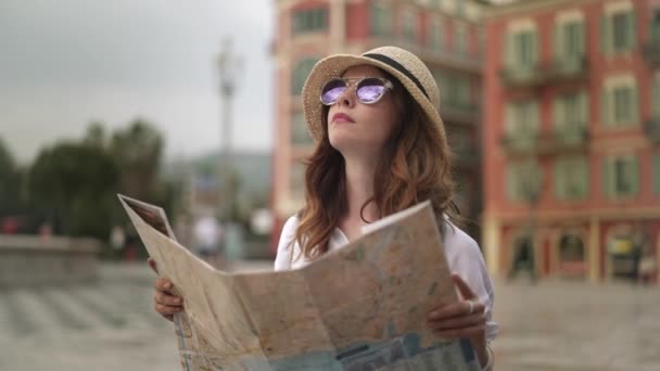 Обаятельный турист с картой смотрит на французское здание в пасмурный день — стоковое видео