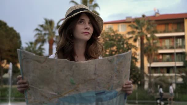 Beautiful tourist girl looking at map in French street near fountain, pan shot — Stock Video