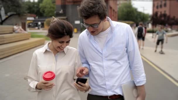 Glada unga par promenader i gatan, dricka kaffe och prata — Stockvideo