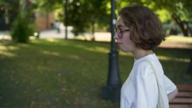 Sigara ve kameraya bakarak hippi kız bardaklarda parkta yürüyüş