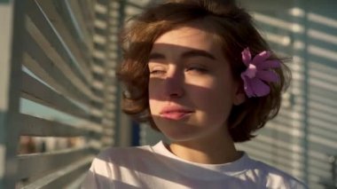 Güzel genç kız saç çiçekli yana doğru görünüyor, o zaman için fotoğraf makinesinin