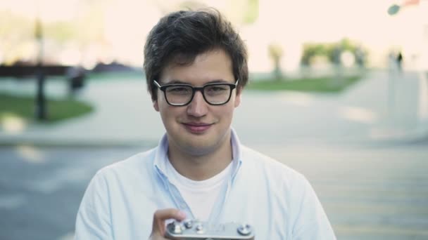 Handsome young man in glasses taking a shot with vintage camera and smiling — Stock Video