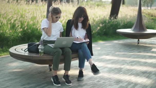 Duas mulheres bonitas e inteligentes trabalhando com laptop ou estudando fora — Vídeo de Stock