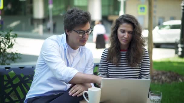 Jovens parceiros de negócios discutindo seu projeto no café de verão — Vídeo de Stock