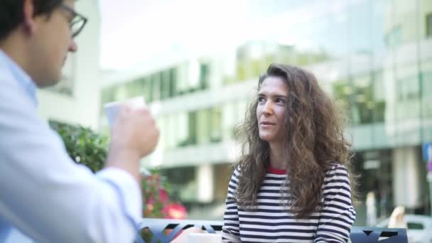 Mujer bastante joven contando emocionante historia a su joven amigo en la cafetería de verano — Vídeos de Stock