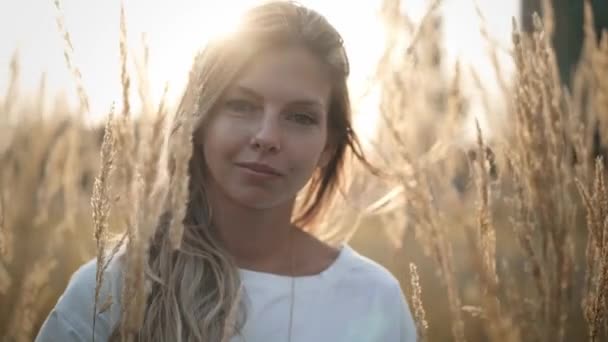Ruhige junge blonde Frau blickt in die Kamera, die auf einem Feld steht — Stockvideo