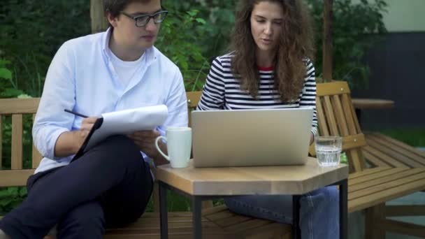 Jovens colegas de trabalho trabalhando fora com laptop e área de transferência, incline-se — Vídeo de Stock