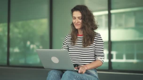 Jonge vrouw in jeans video bellen naar haar vriend zitten buiten — Stockvideo